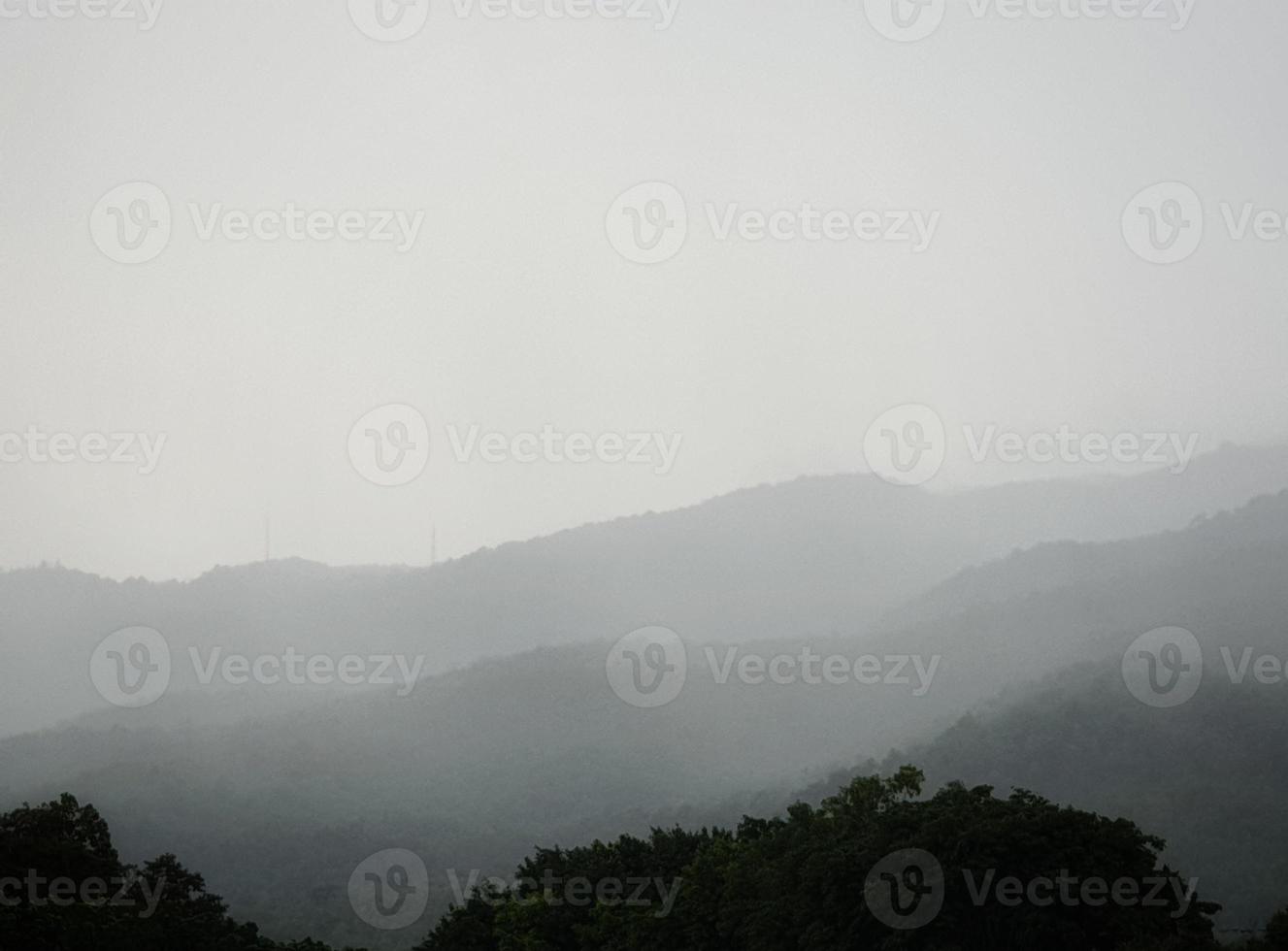 vackert mörkgrått bergslandskap med dimma och skog. foto