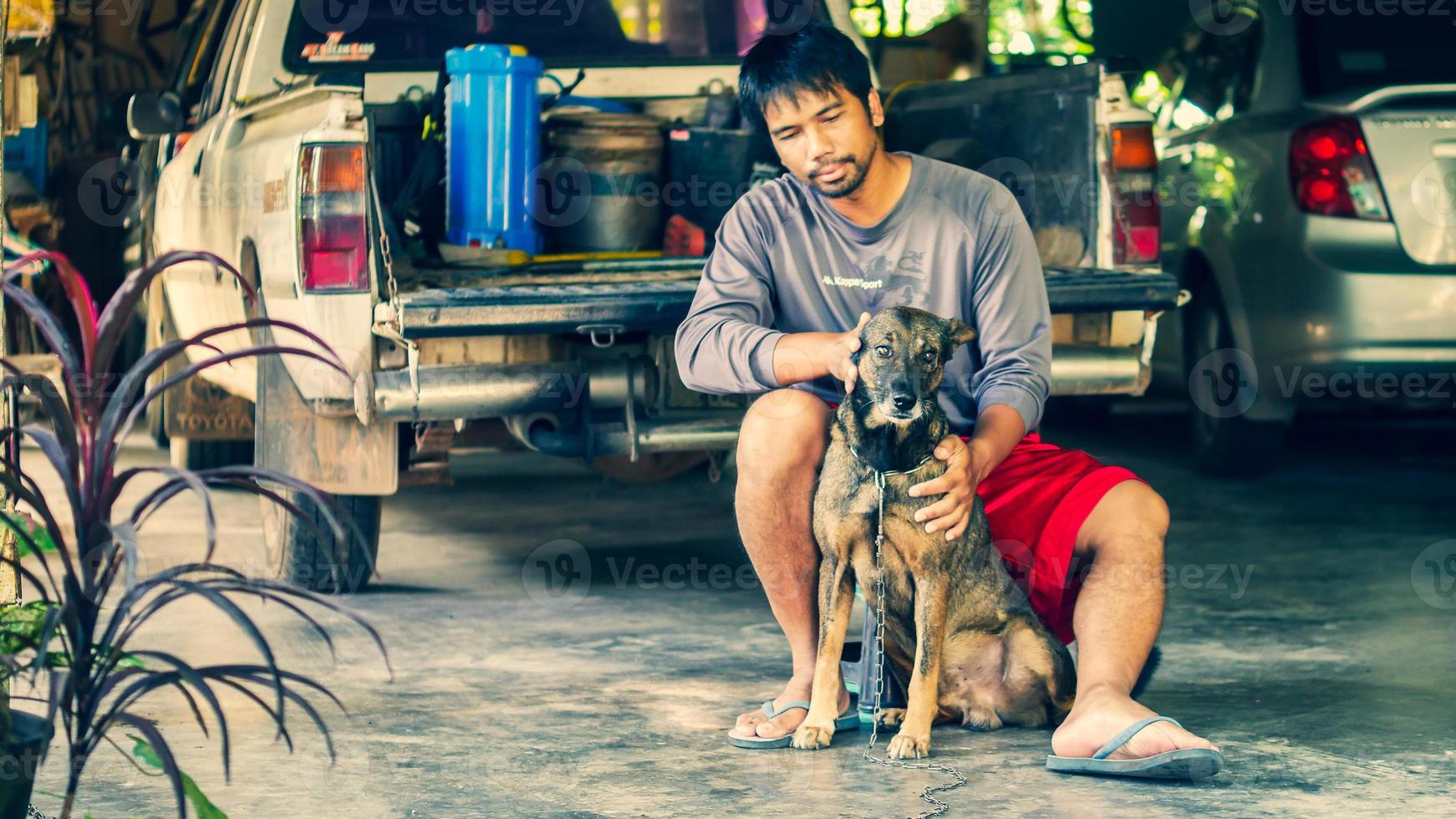 asiatisk man sitter med en hund i sitt hem foto