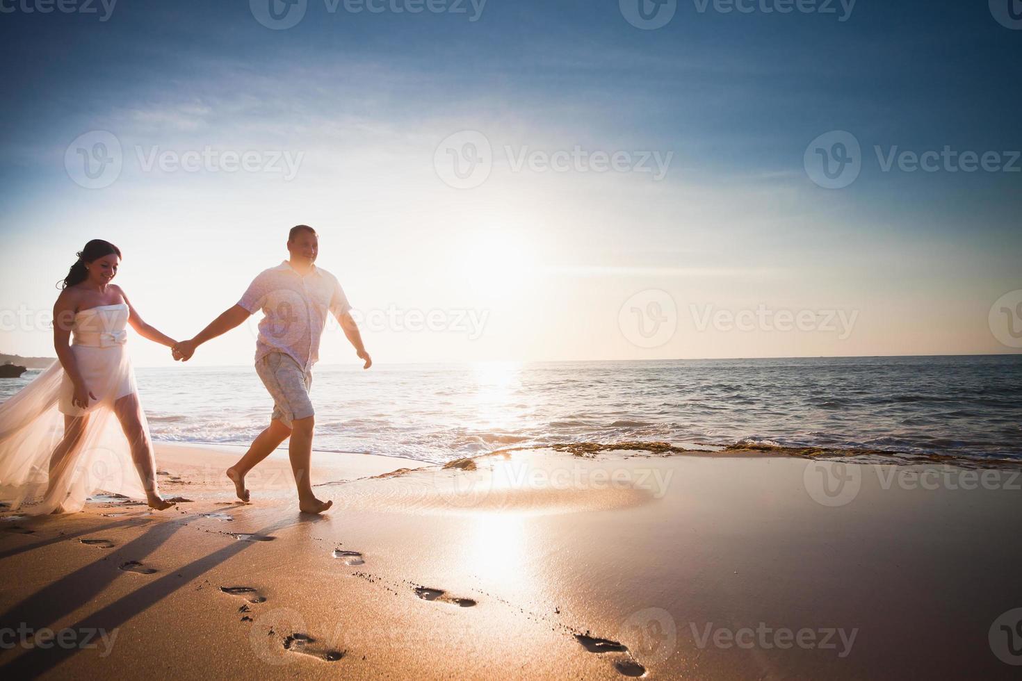 par för bröllopsresa gifte sig precis som springer på stranden foto