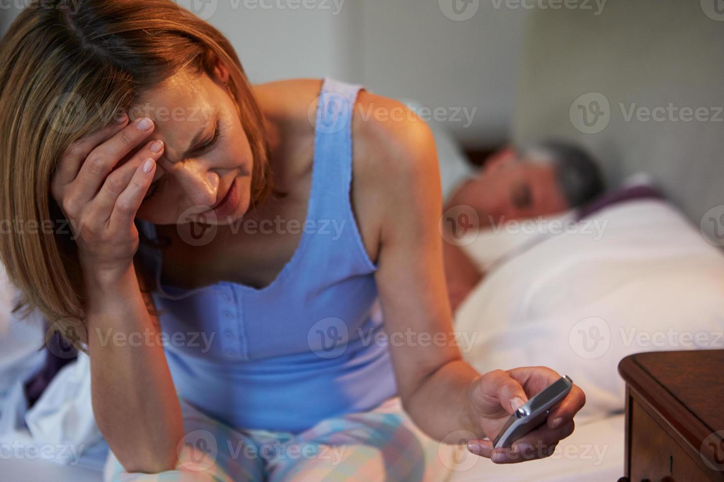 en kvinna som lider av sömnlöshet medan mannen sover foto