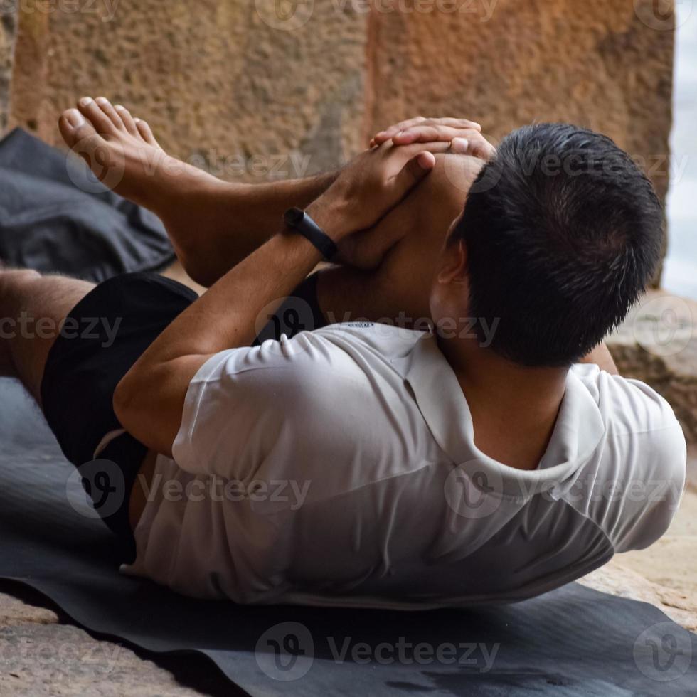 inspirerad indisk ung man gör yoga asanas i lodhi garden park, new delhi, indien. ung medborgare tränar utanför och står i yoga sidovinkel pose. fitness utomhus och livsbalans koncept foto