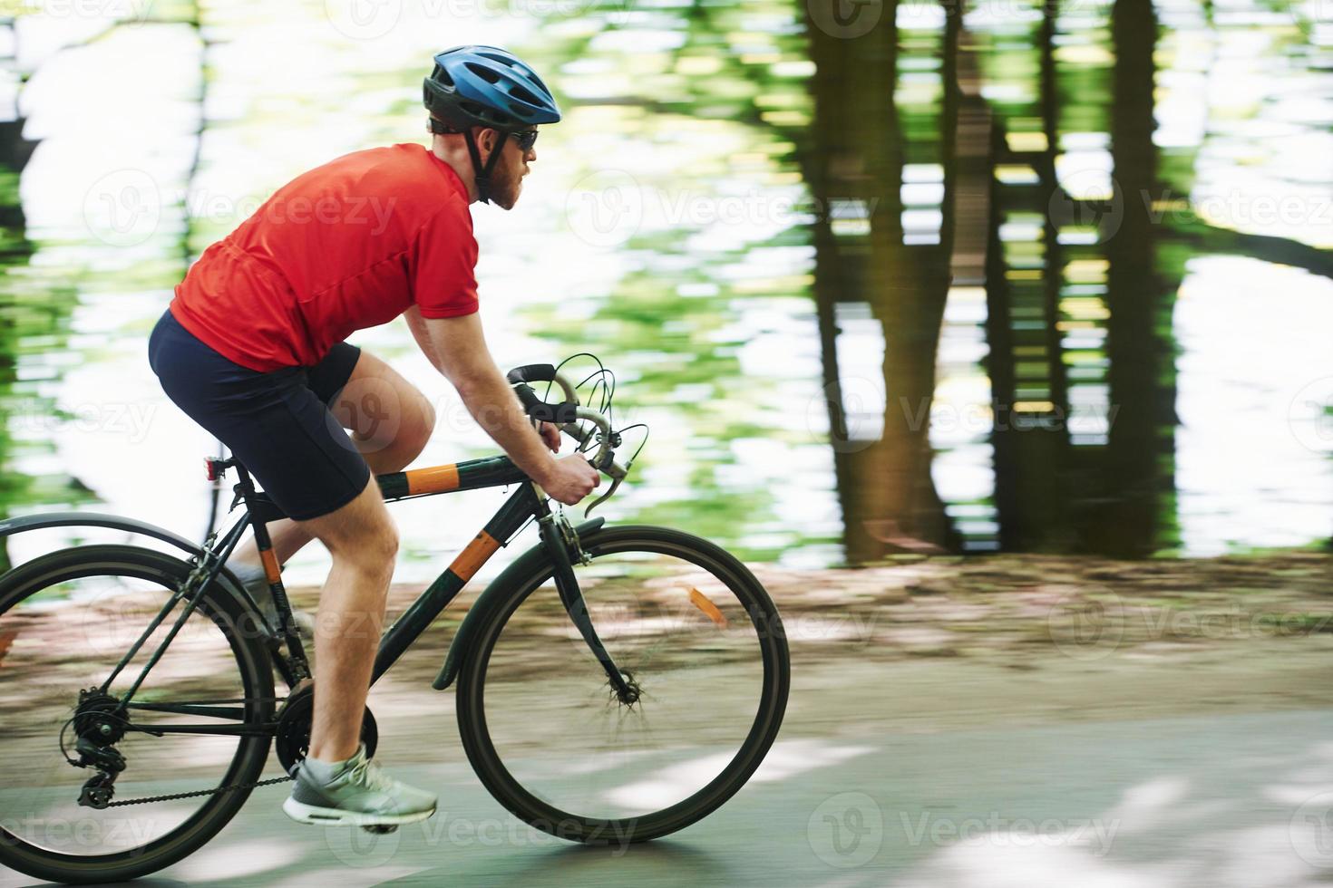 skön känsla. cyklist på en cykel är på asfaltvägen i skogen på en solig dag foto