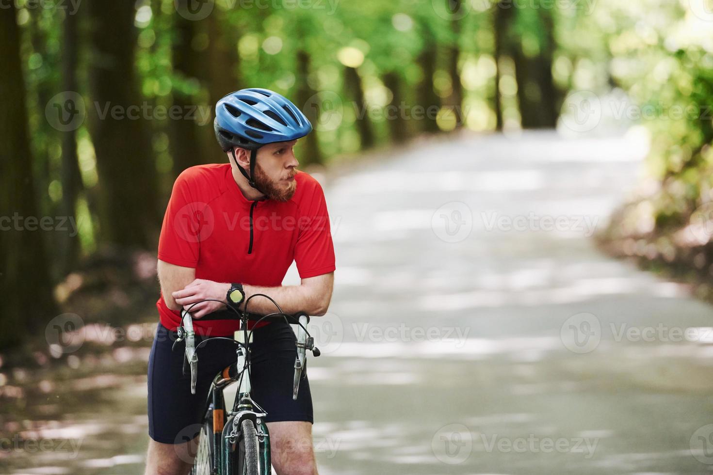 väntar på en vän. cyklist på en cykel är på asfaltvägen i skogen på en solig dag foto