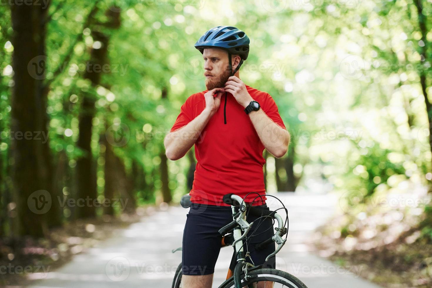 på landsbygden. cyklist på en cykel är på asfaltvägen i skogen på en solig dag foto