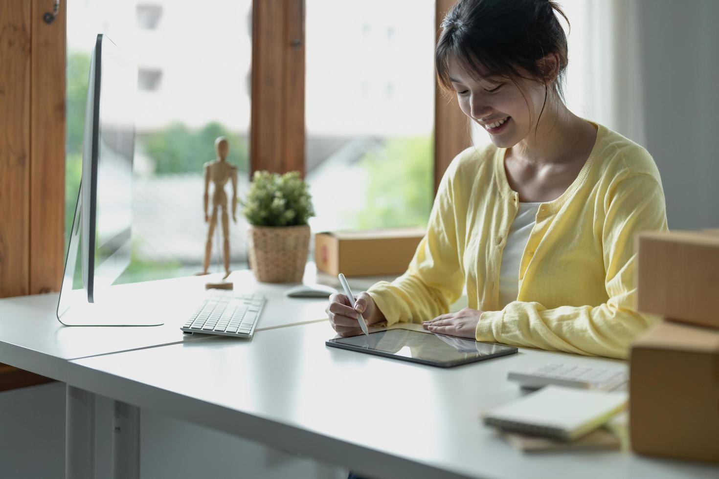 ung asiatisk kreativ designer håller penna ritning på skärmen av digital surfplatta medan du sitter på moderna kontor. foto