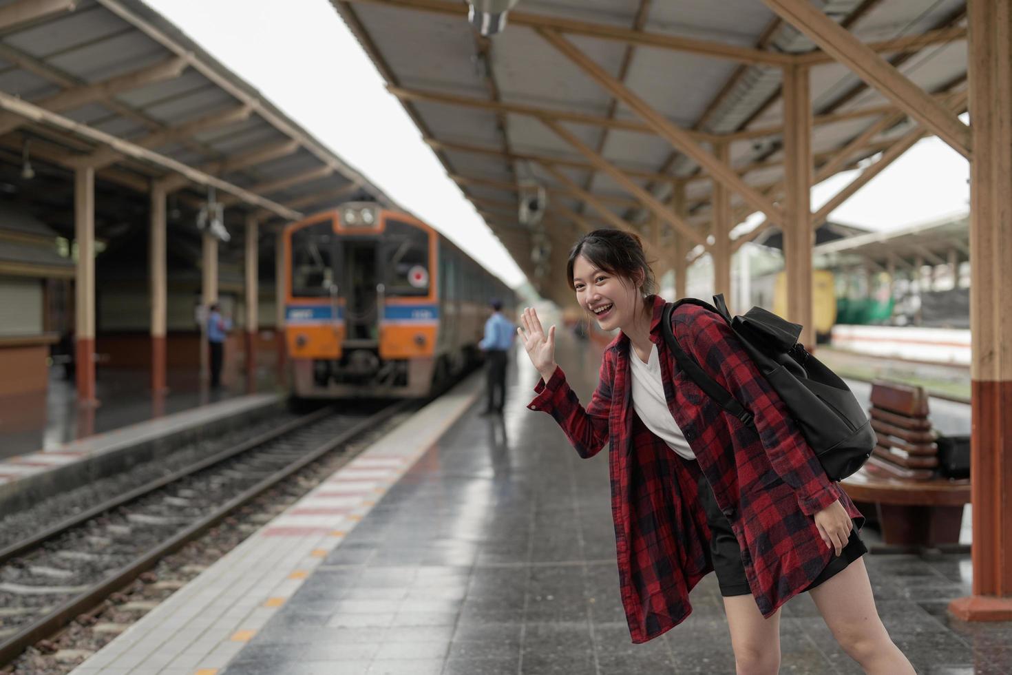 glad asien kvinna resenär känner lycka innan du går för att resa på tågstationen, sommarresor och livsstilskoncept foto