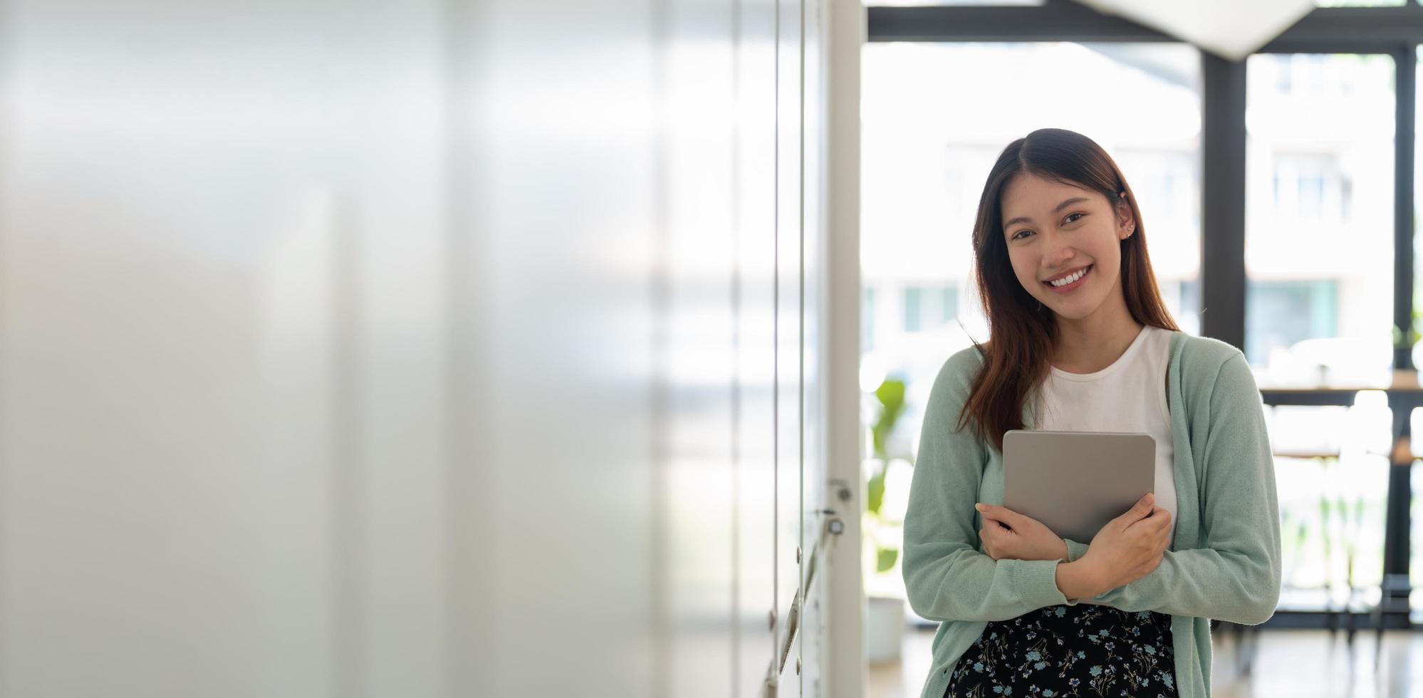 porträtt av ung glad attraktiv asiatisk student som ler och tittar på kameran. asiatisk kvinna i själv framtida utbildning eller personligt lärande koncept. baner foto