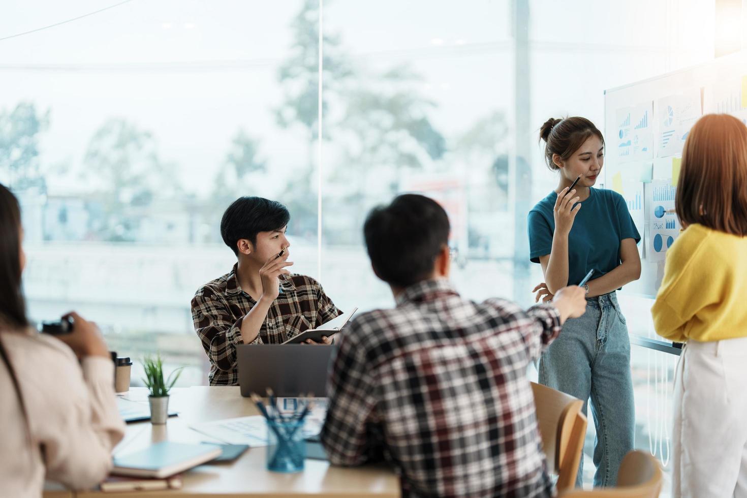 unga kreativa mångfaldiga gruppmöte och titta på projekt diskutera eller brainstorma affärsstrategi med post anteckning. workshop för startup team i moderna kontor. glad arbetsplats foto