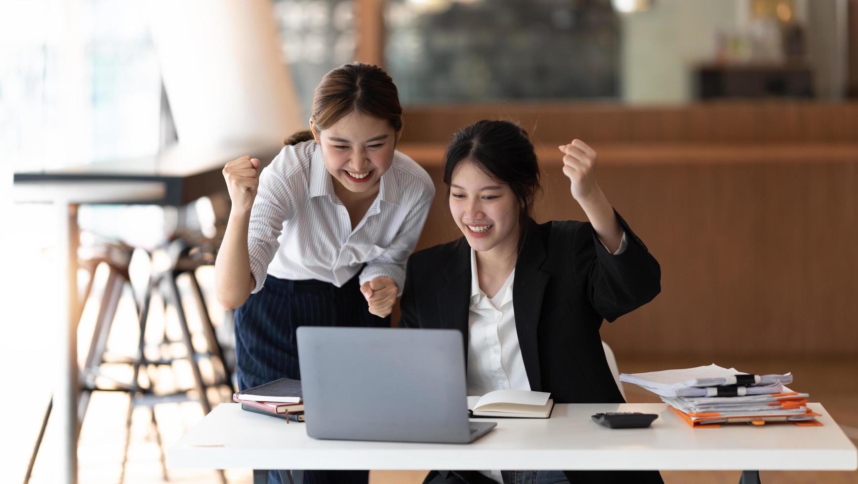 två asiatisk kvinna upphetsad affärsteam fira företagsseger tillsammans på kontoret foto