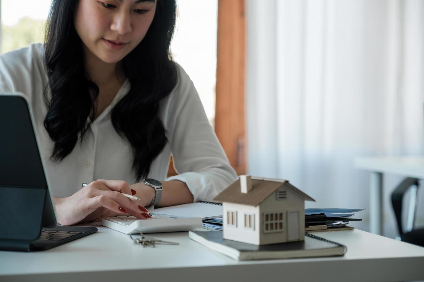 köpa och sälja hus och fastighetspriser koncept. kvinna som använder kalkylator för att räkna hyra, pengar eller hemförsäkringskostnad. beräkning av bolån, lån eller investering. foto