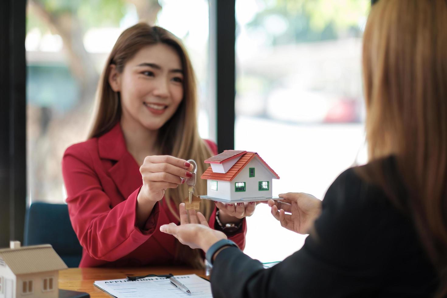 fastighetsmäklare håller husnyckeln till sin klient efter att ha undertecknat kontraktsavtal på kontoret, koncept för fastigheter, flytta hem eller hyra egendom. foto