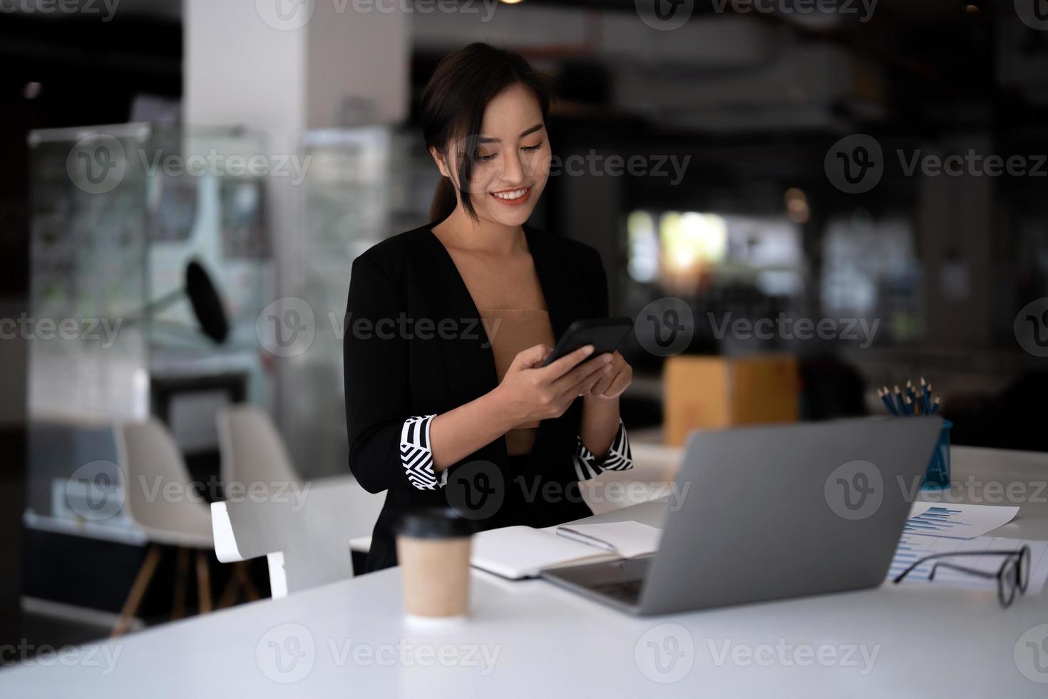 asiatisk affärskvinna som använder mobiltelefon när hon kollar ett e-postmeddelande eller sociala medier på internet. redovisning finansiellt koncept. foto