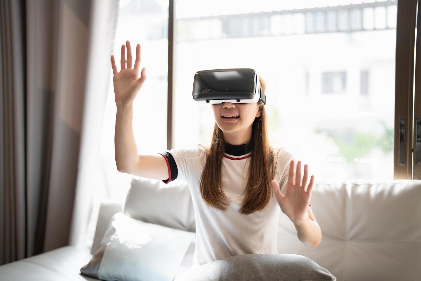 excitera asiatisk kvinna som spelar onlinespel med vr-glasögon och handkontroll hemma foto