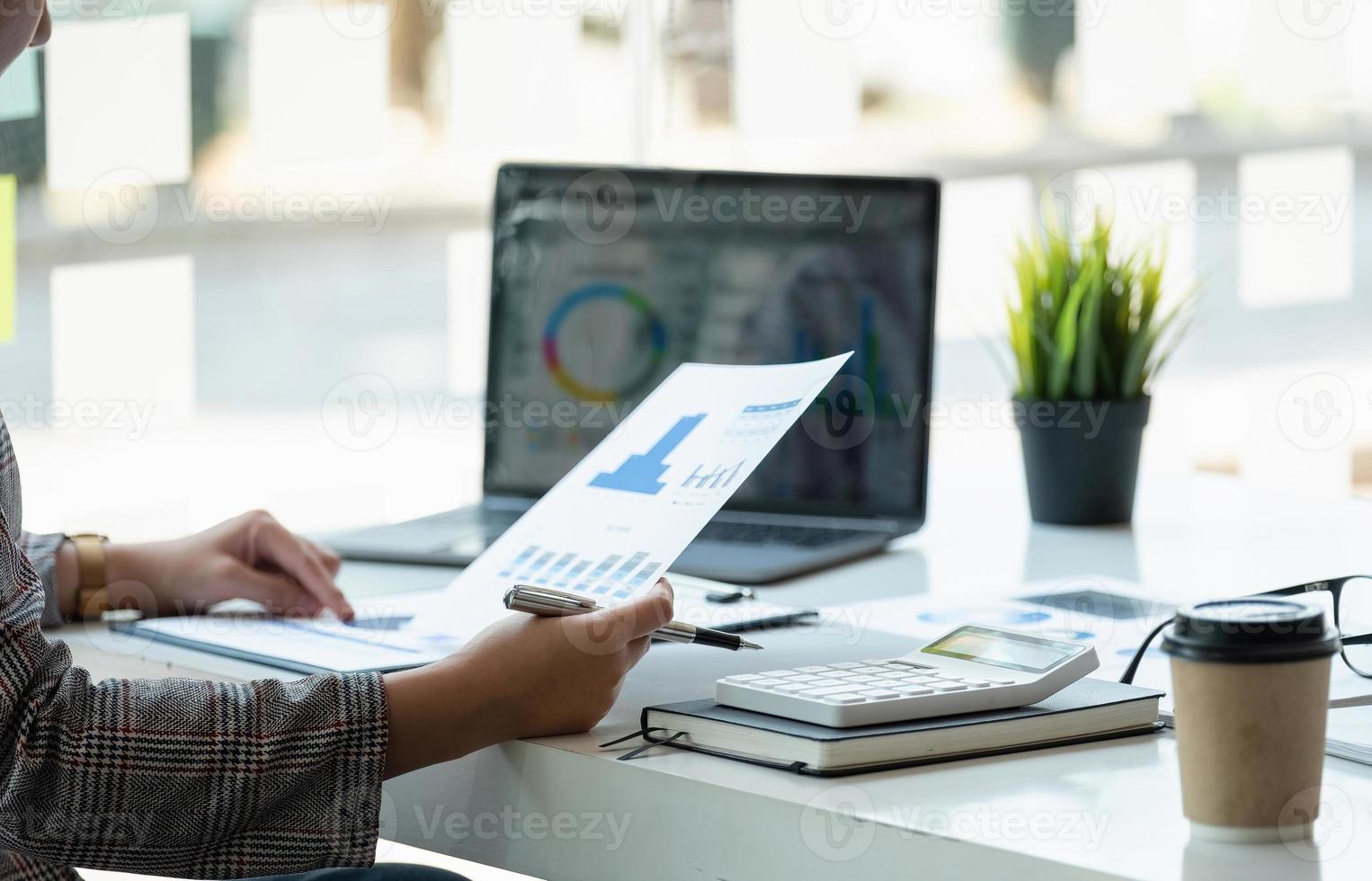 affärskvinna som använder miniräknare för matematikfinansiering på träbord i kontor och affärsarbetsbakgrund, skatt, redovisning, statistik och analytisk forskningskoncept foto