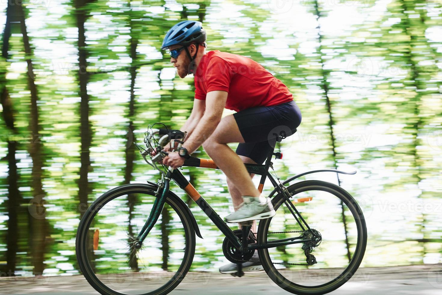 galen fart. cyklist på en cykel är på asfaltvägen i skogen på en solig dag foto