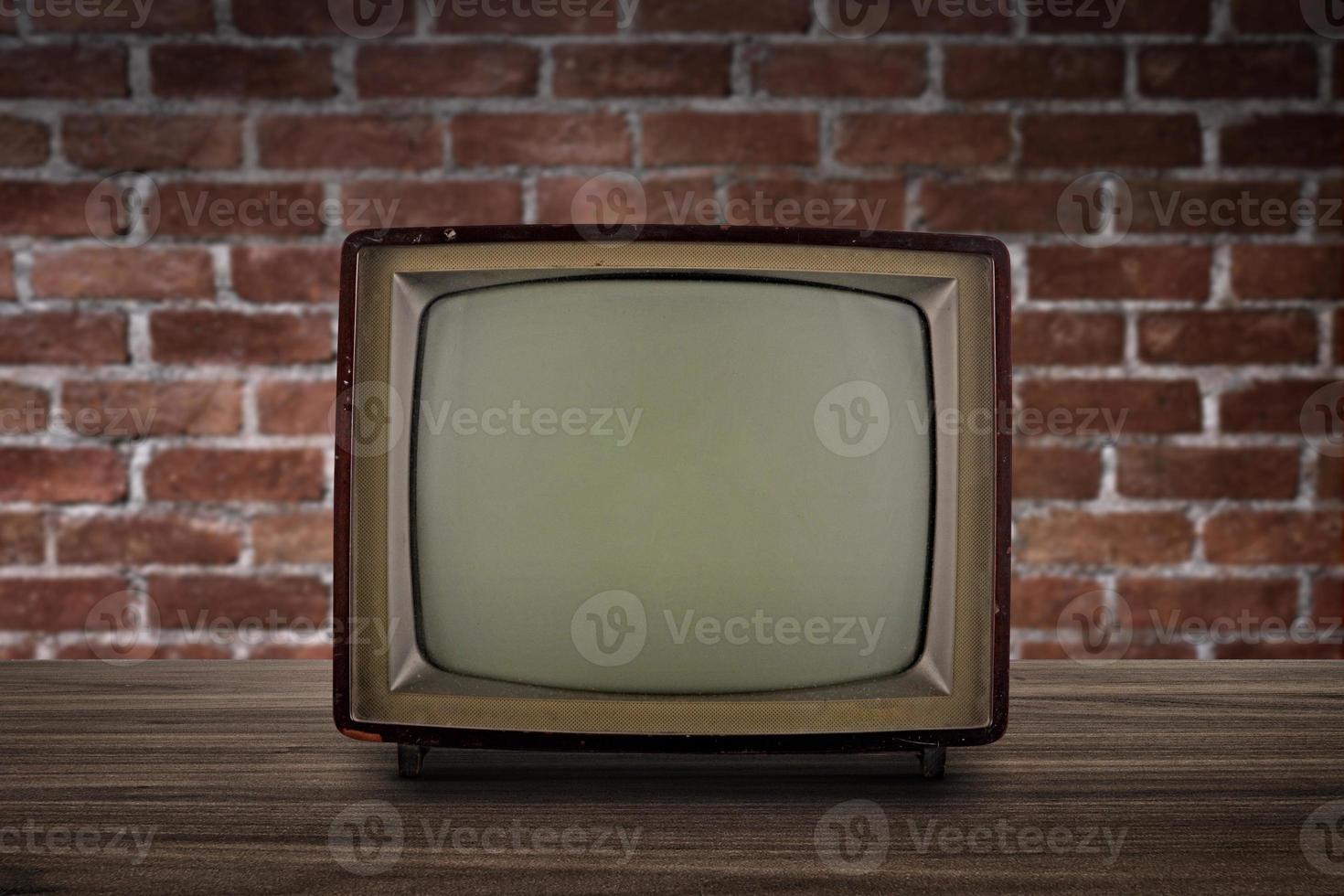 retro gammal tv på trägolv med tegelvägg, retro, vintage tv-stil foto