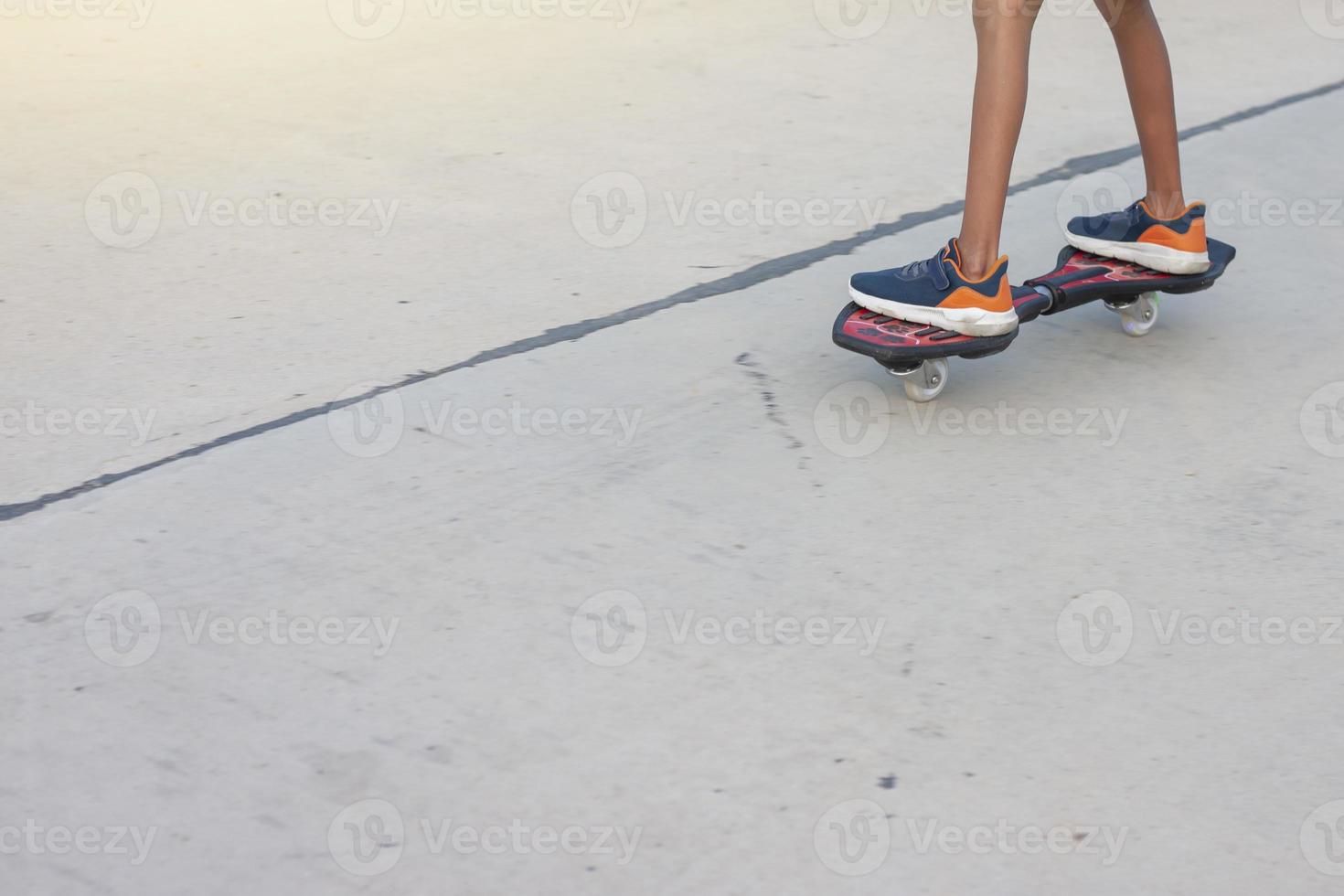 benen på en asiatisk pojke som har roligt med att spela snakeboard på cementgolvet är en avkopplande livsstil på semestern. foto