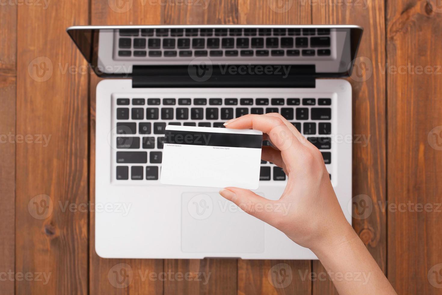 kvinnlig hand som håller en kortbetalning på en bärbar dator foto
