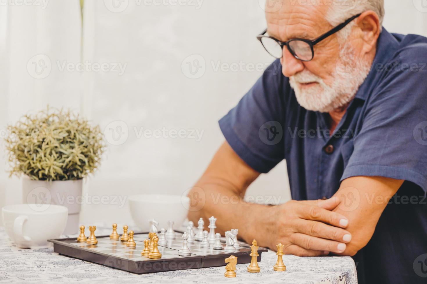 smart äldre spelar schackbrädspel hemma för att träna hjärnminne och tänka glada leende selektivt fokus på schackpjäs. foto