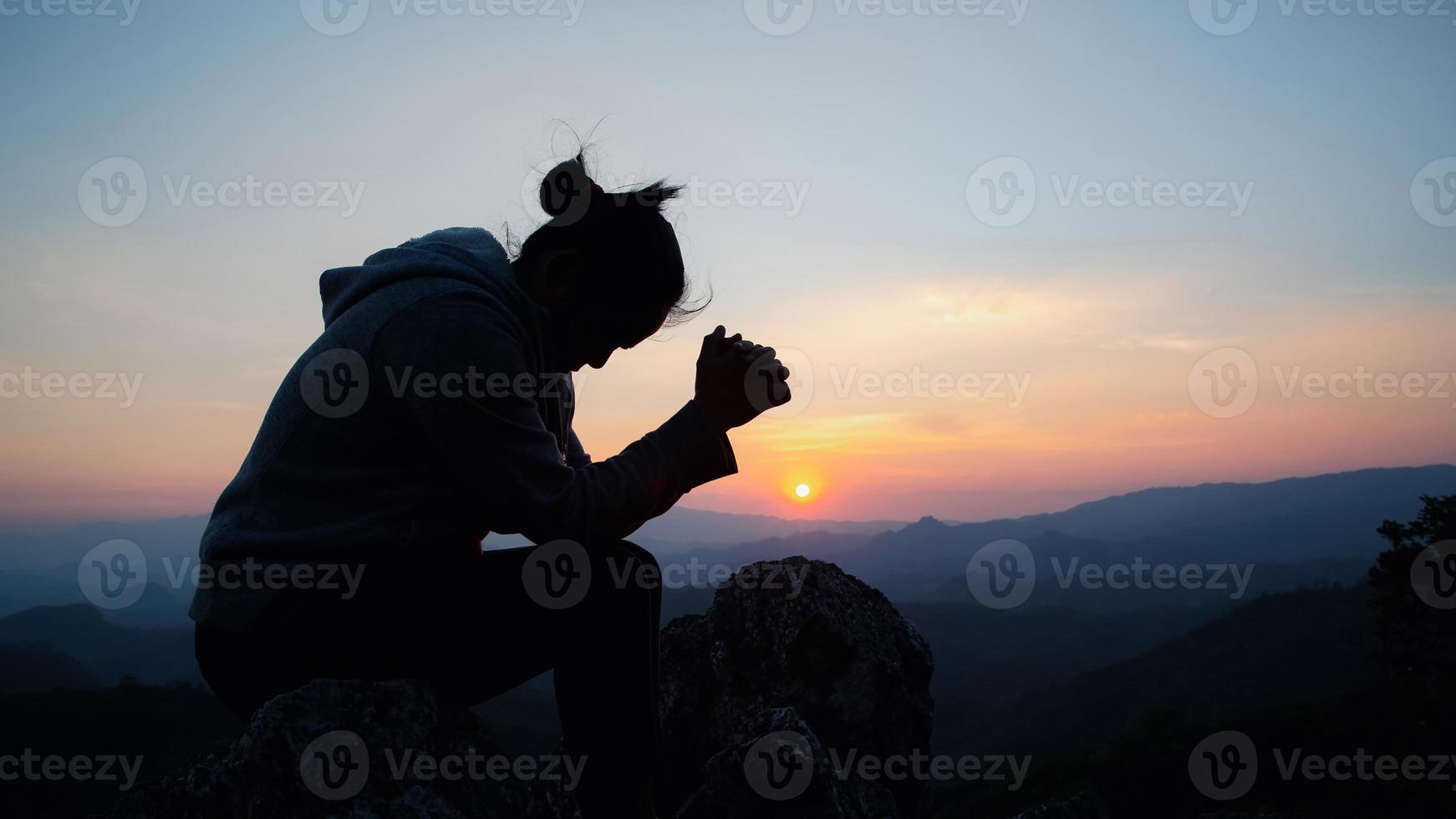 kristen kvinna ber tillbedjan vid solnedgången. händerna vikta i bön. dyrka gud med kristen koncept religion. foto