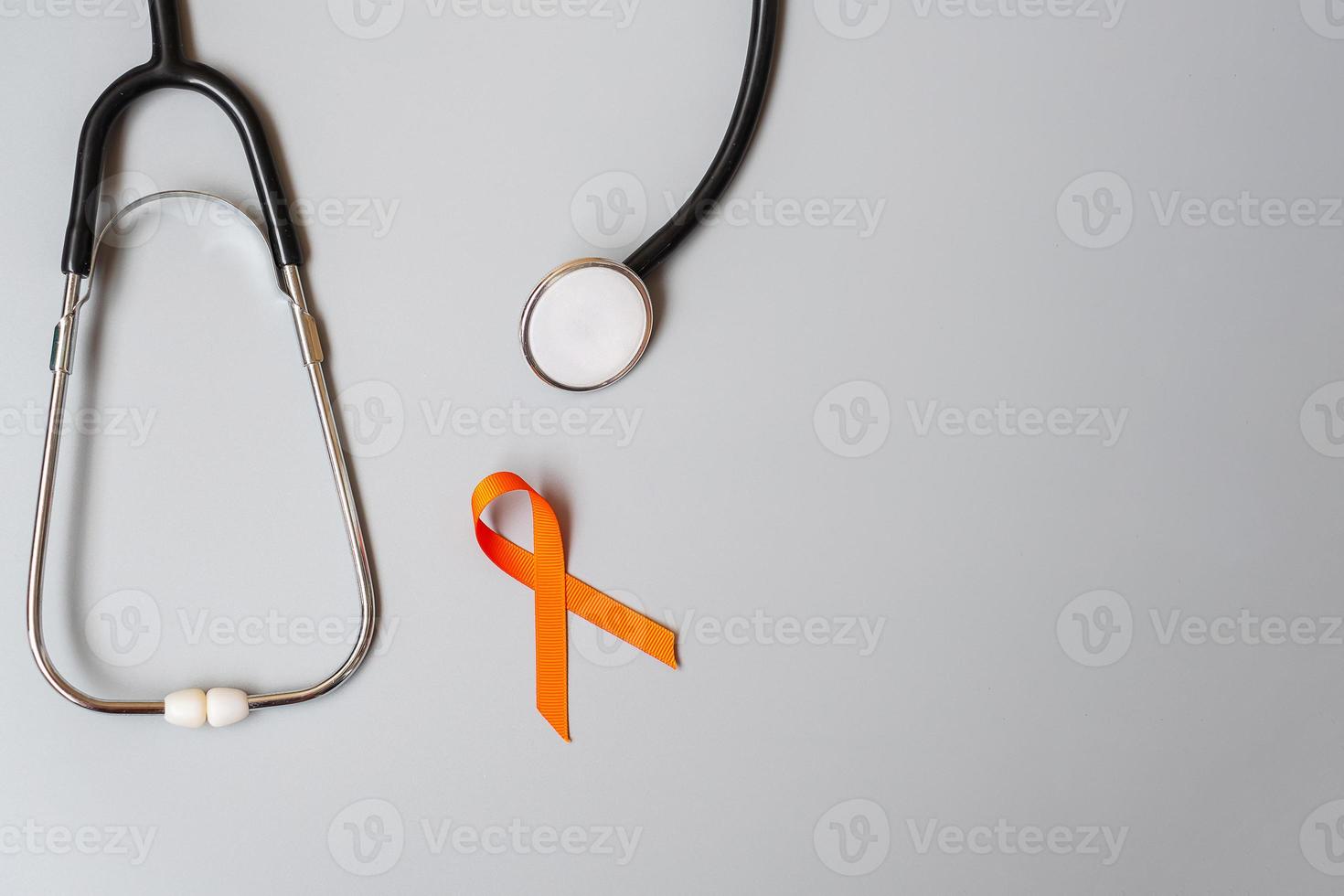 leukemi, njurcancerdagen, multipel skleros i världen, crps, månad för medvetenhet om självskador, orange band med stetoskop för att stödja människor som lever och sjukdomar. hälsovård och världen cancer dag koncept foto