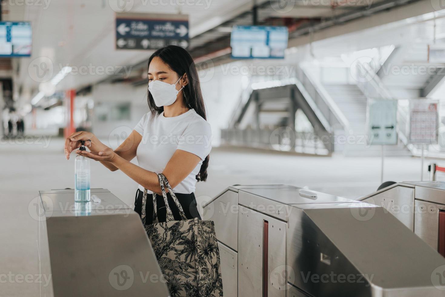 asiatisk kvinna som bär skyddsmask står och väntar på sky train. kvinna som bär kirurgisk skyddsmask i en kollektivtrafik. nytt normalkoncept. foto