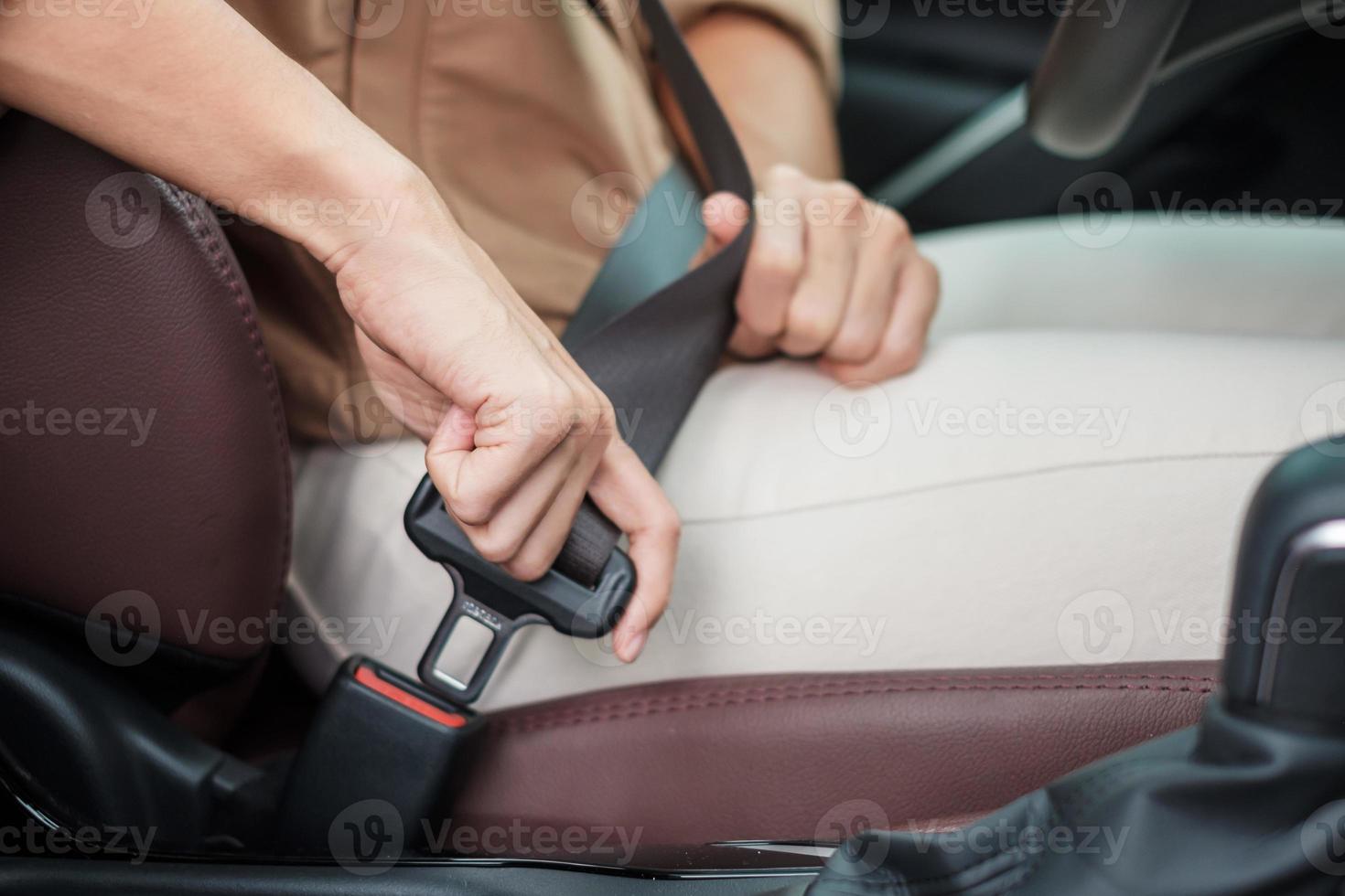 kvinna förare hand fäst säkerhetsbälte under sittande i en bil och körning på vägen. säkerhet, resa, resa och transport koncept foto