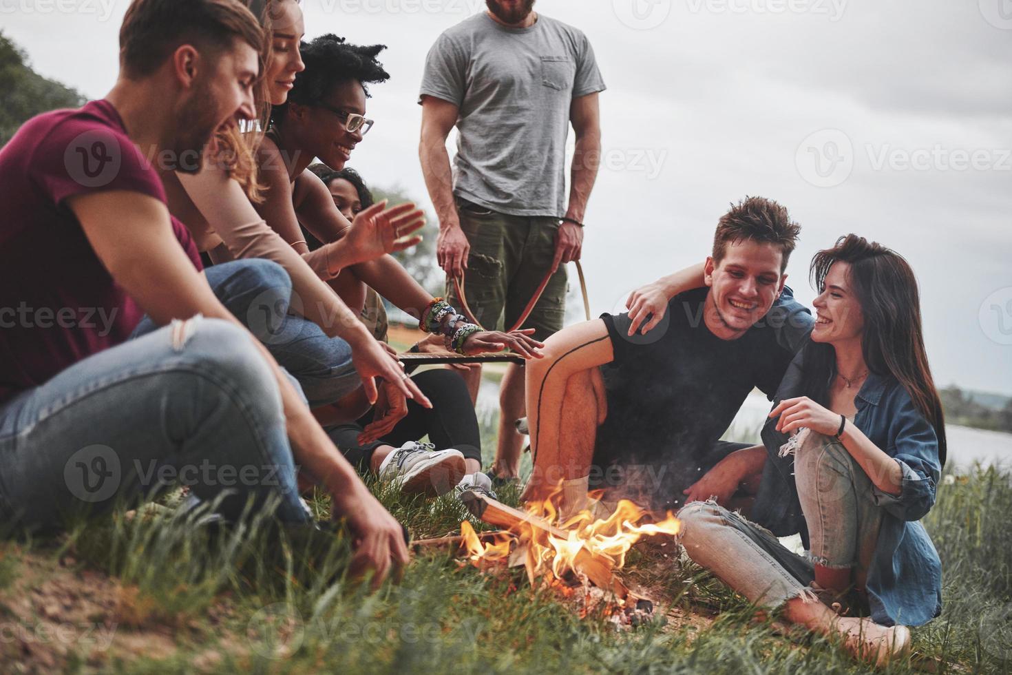 mysig atmosfär. grupp människor har picknick på stranden. vänner har kul på helgen foto