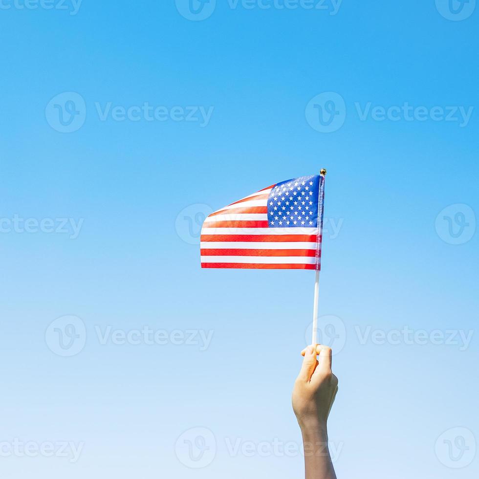 hand som håller USAs flagga på blå himmel bakgrund. USA semester för veteraner, minnesmärke, oberoende och labor day koncept foto