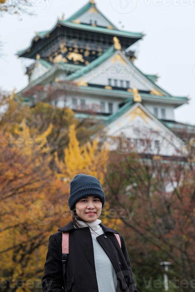 ensam kvinna turist reser på osaka slott under höstsäsongen, asiatisk resenär besök i osaka city, japan. semester, destination och resekoncept foto