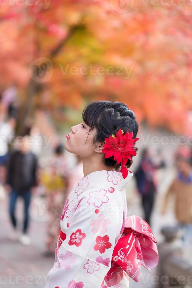 ung kvinna turist bär kimono njuter med färgglada löv i kiyomizu dera tempel, kyoto, japan. asiatisk tjej med frisyr i traditionella japanska kläder under höstens lövverk säsong foto