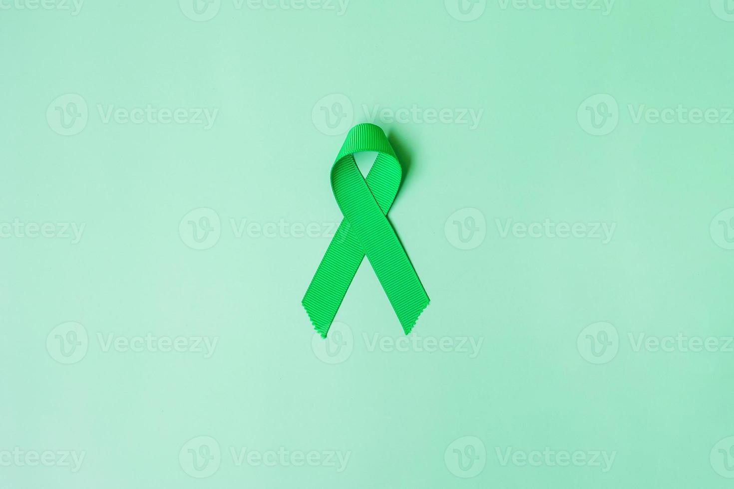grönt band på grön bakgrund för att stödja människor som lever och sjukdom. lever, gallblåsa gallvägscancer och organdonation medvetenhet månad koncept foto