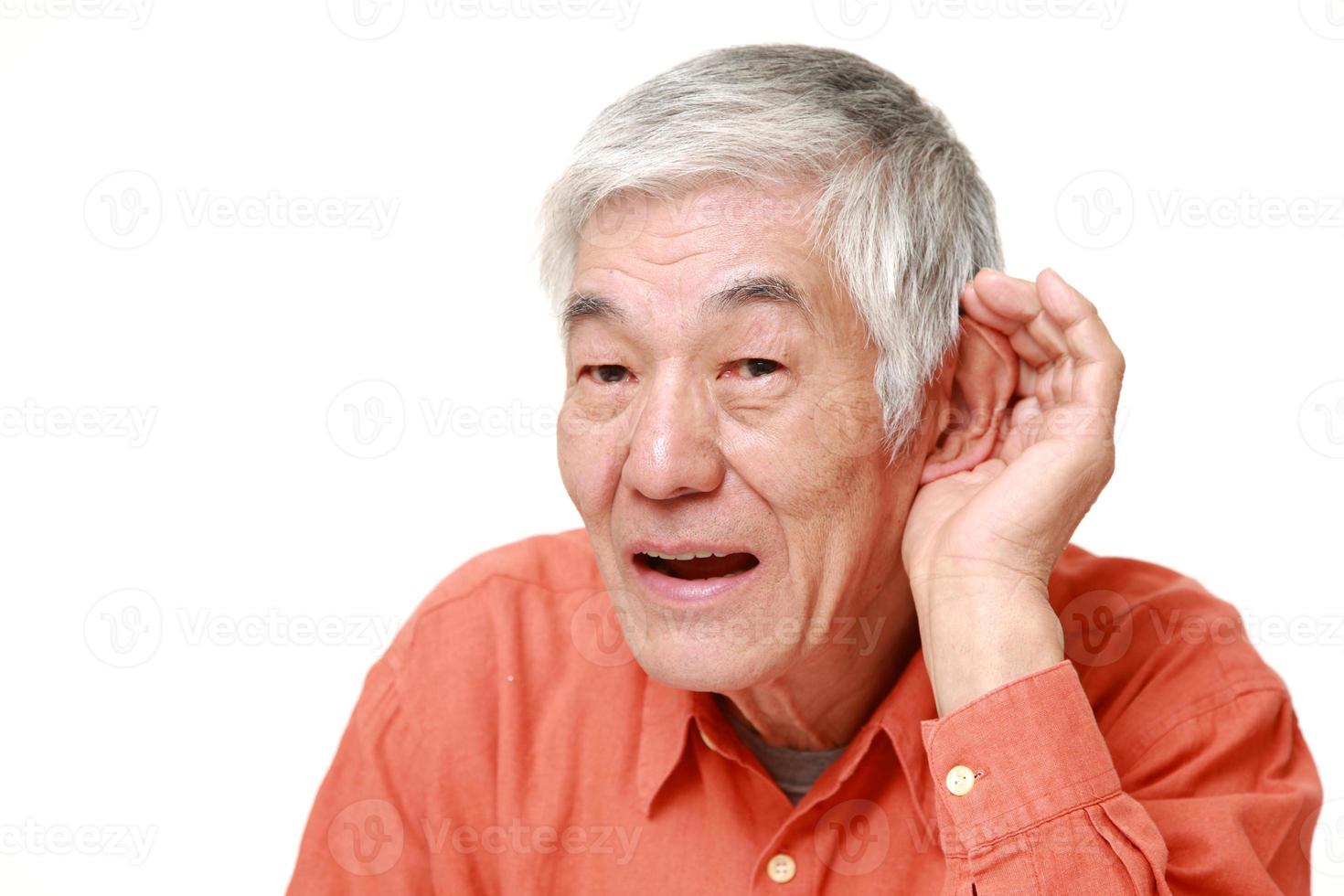 äldre japansk man med handen bakom örat lyssnar noga foto