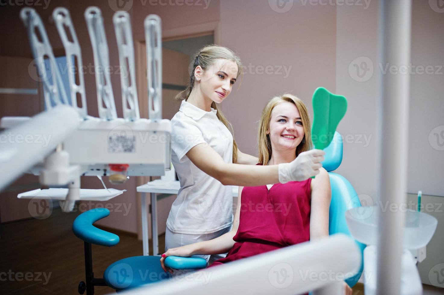 vacker tandläkare som visar sin patients nya tänder genom spegeln i tandskåpet. foto