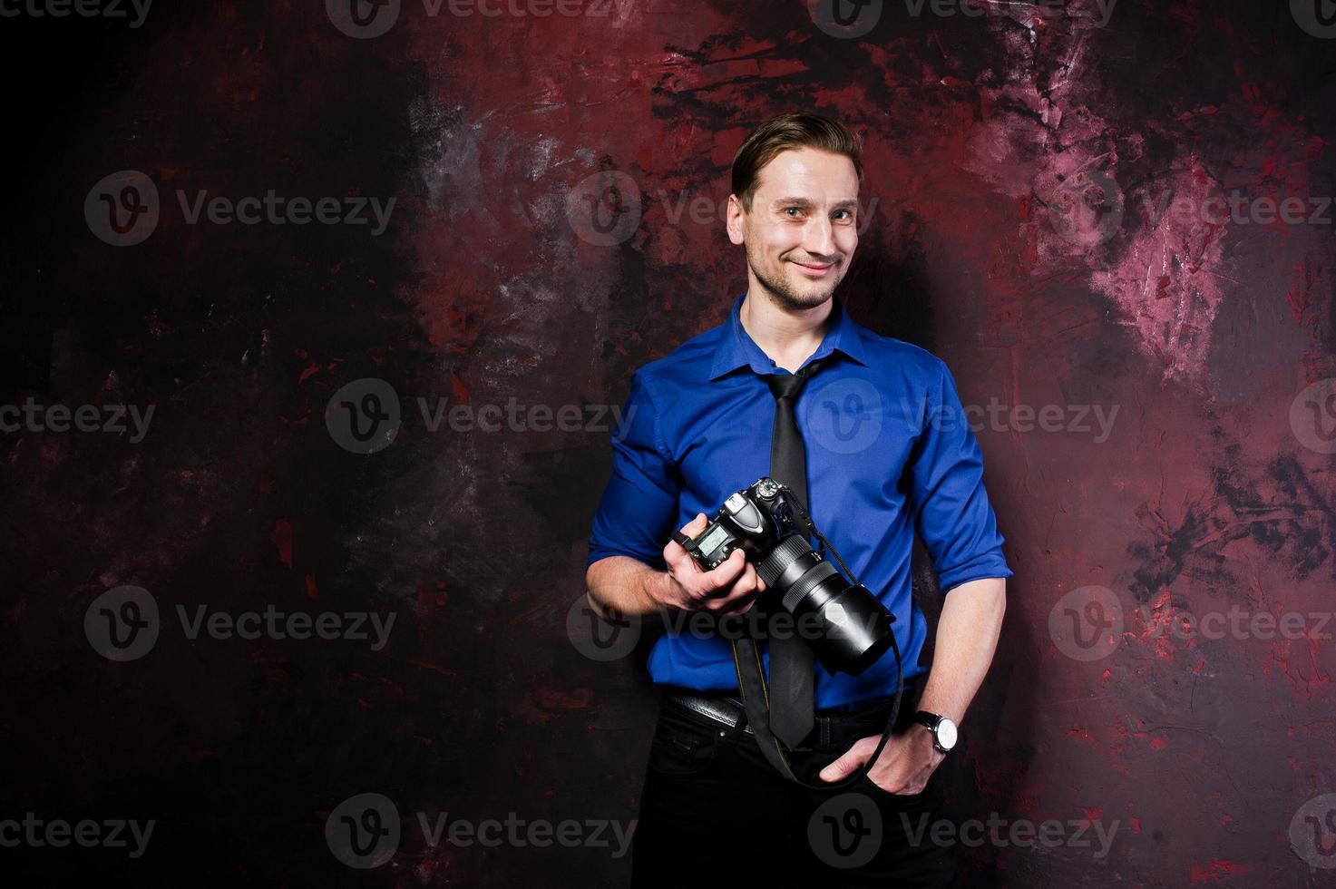 studio porträtt av snygg professionell fotograf man med kamera, bära på blå skjorta och slips. foto