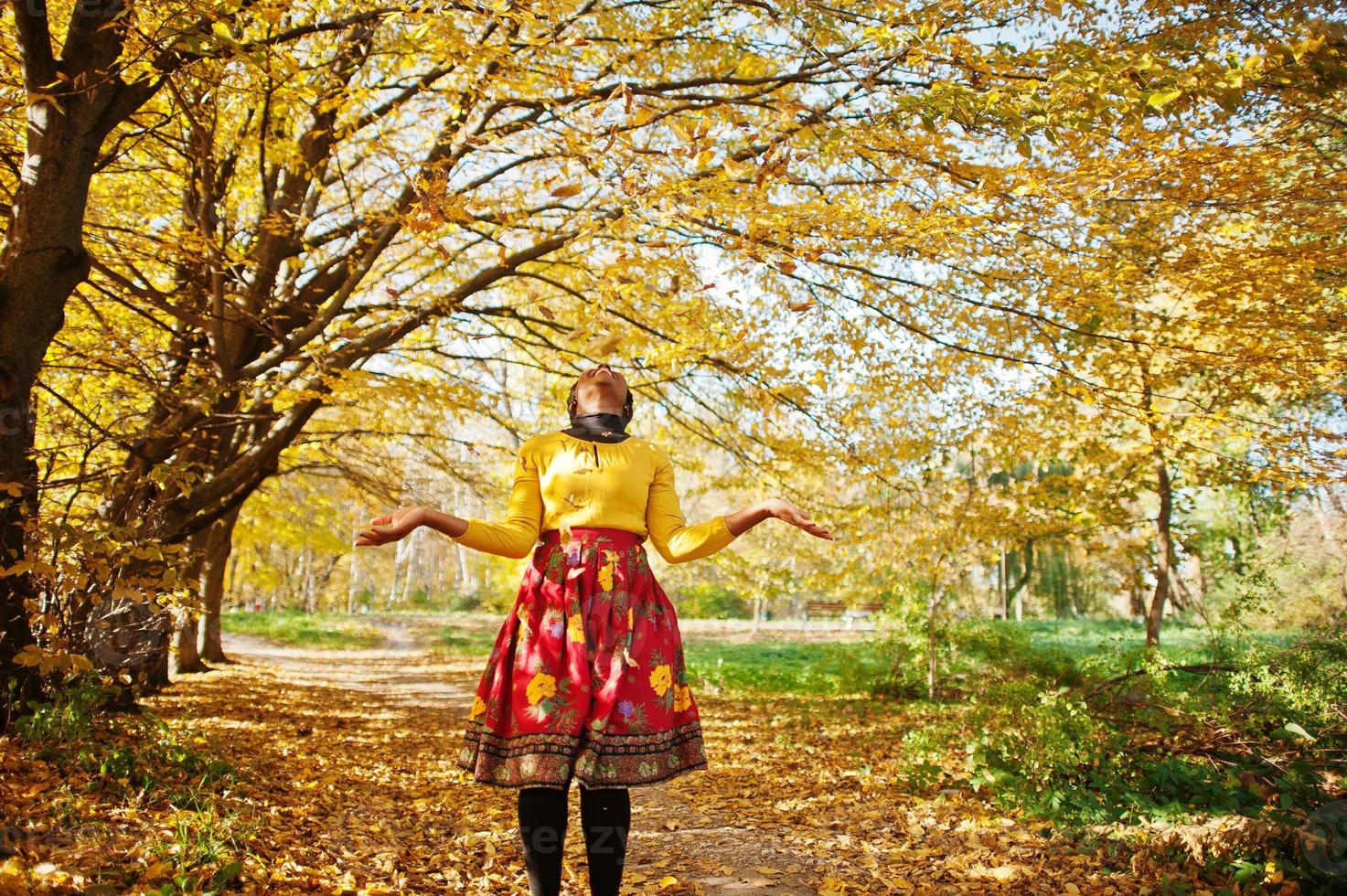 afrikansk amerikansk flicka på gul och röd klänning på gyllene höst höst park. foto