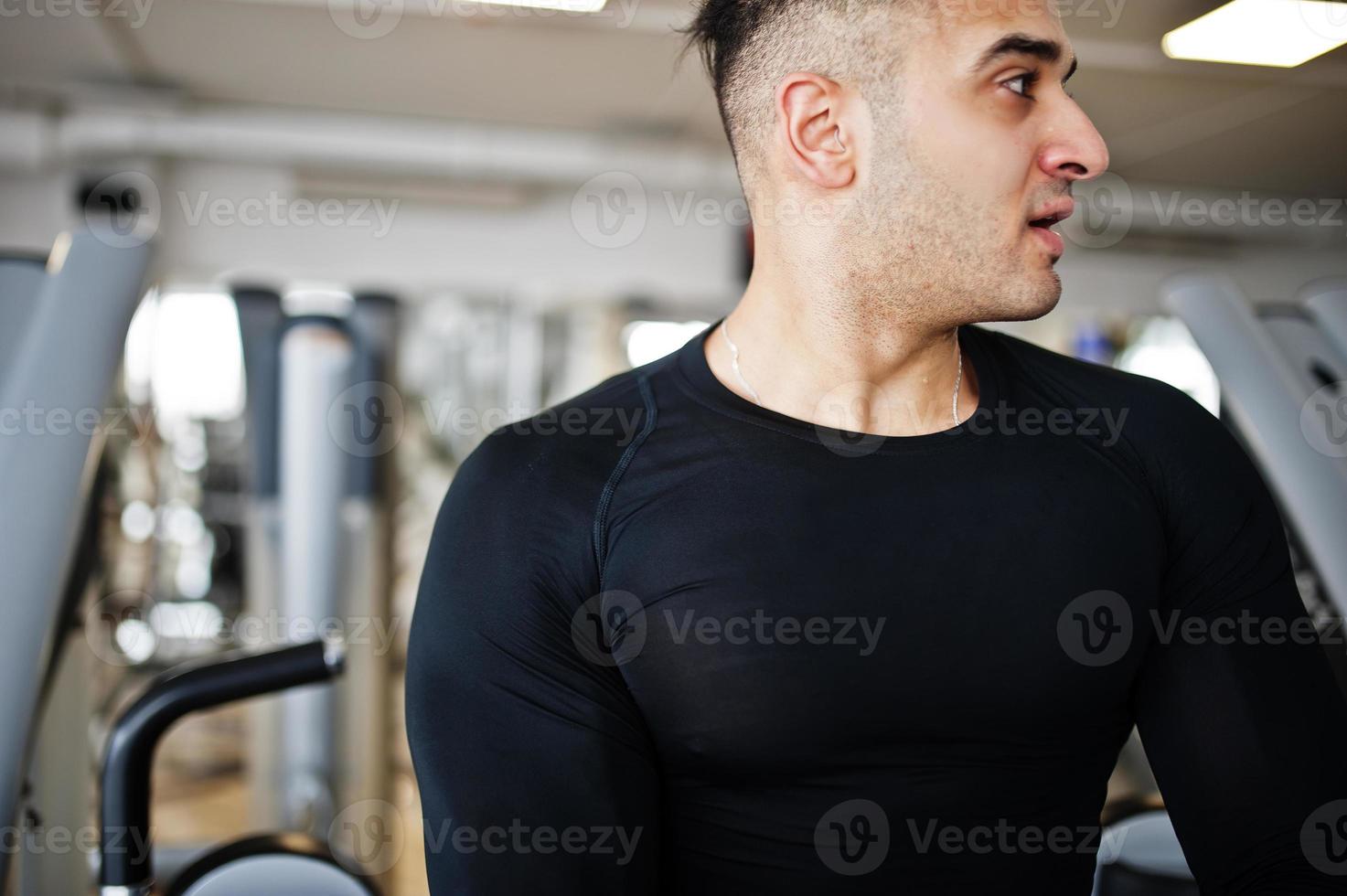 muskulös arabisk man tränar och tränar på fitnessmaskin i modernt gym. foto