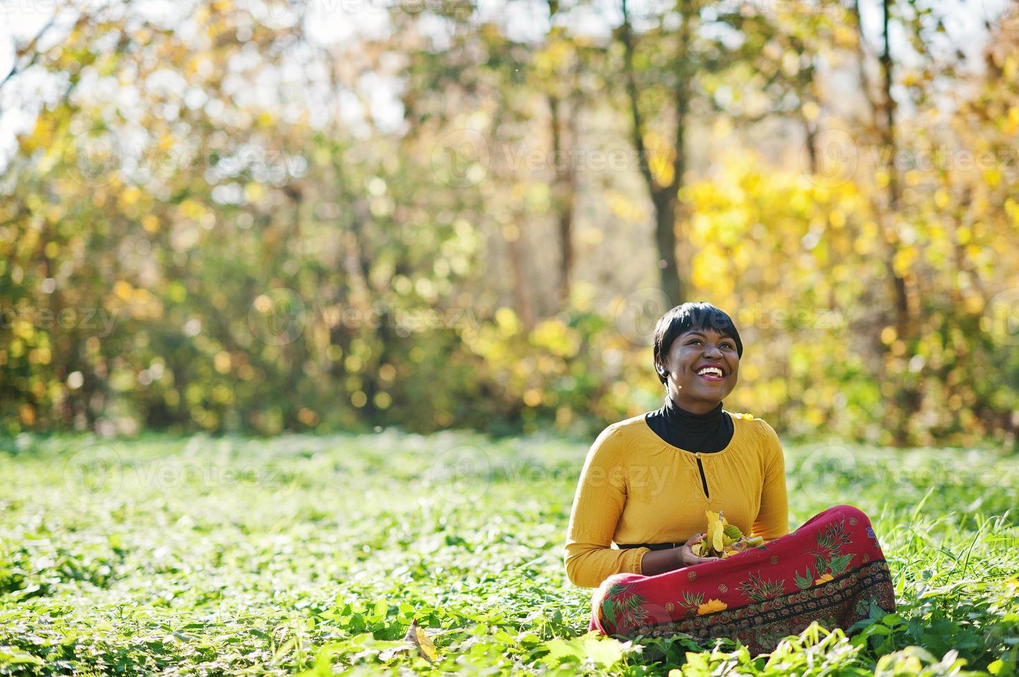 afrikansk amerikansk flicka på gul och röd klänning på hösten höst park. foto