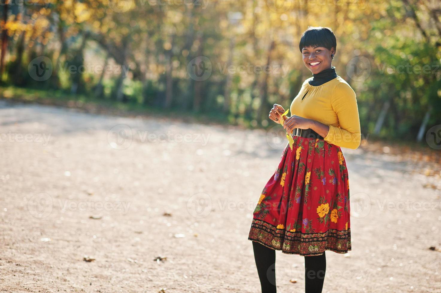 afrikansk amerikansk flicka på gul och röd klänning på gyllene höst höst park. foto