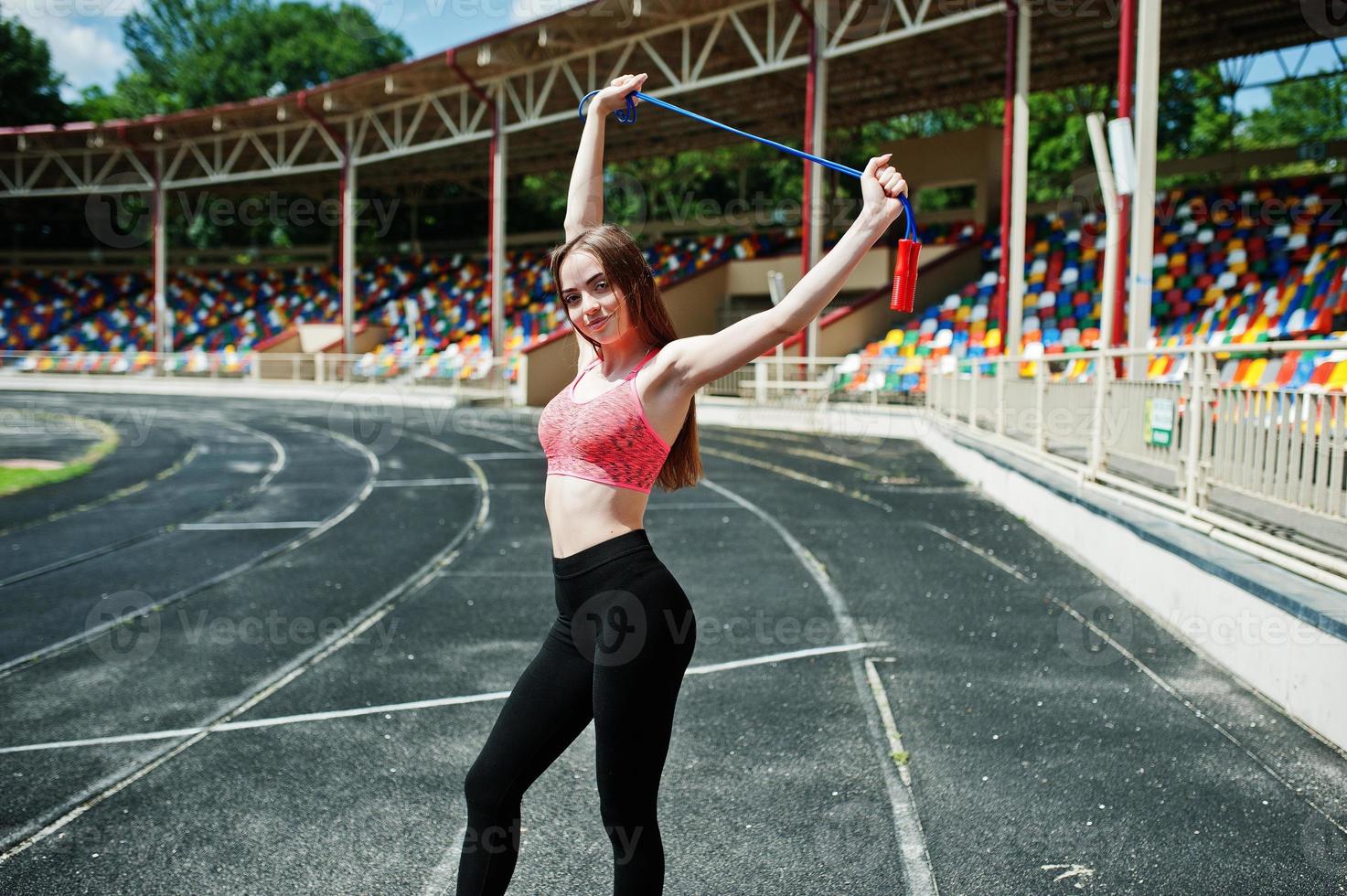 fitness sportig tjej i sportkläder på en fotbollsstadion utomhussporter. glad sexig kvinna träning med rep. foto