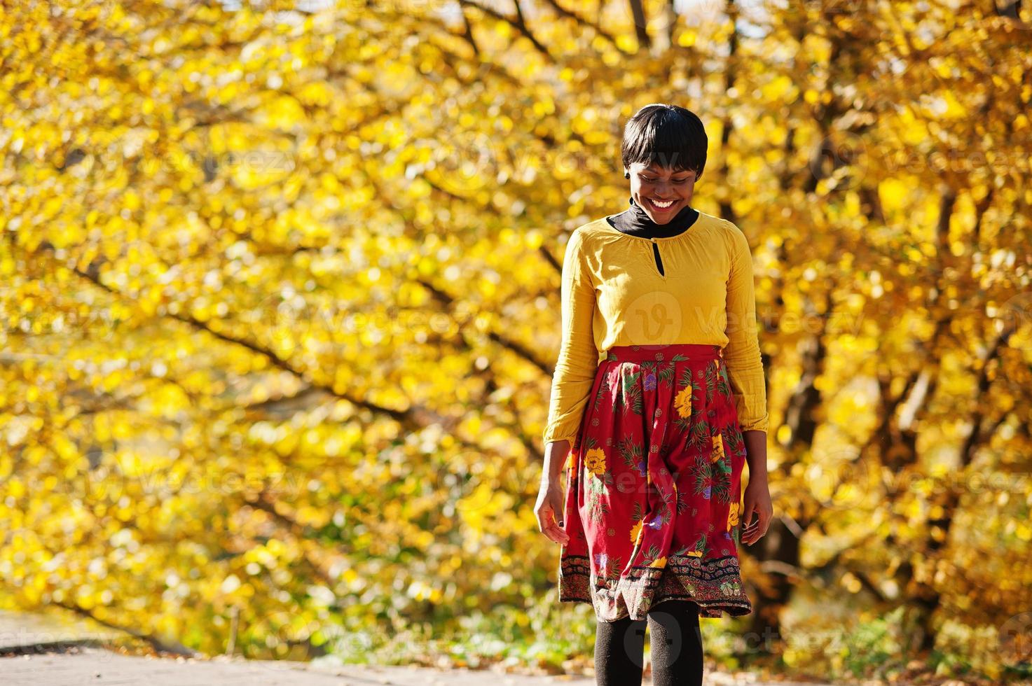 afrikansk amerikansk flicka på gul och röd klänning på gyllene höst höst park. foto