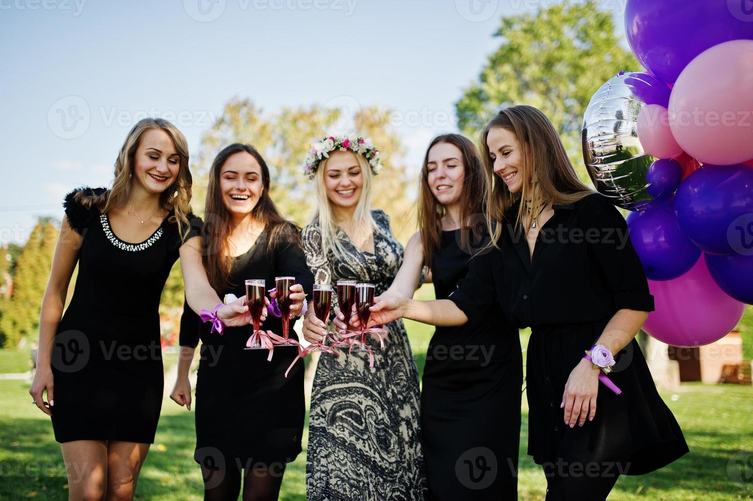 fem flickor bär på svart med ballonger dricker röd champagne på möhippo. foto