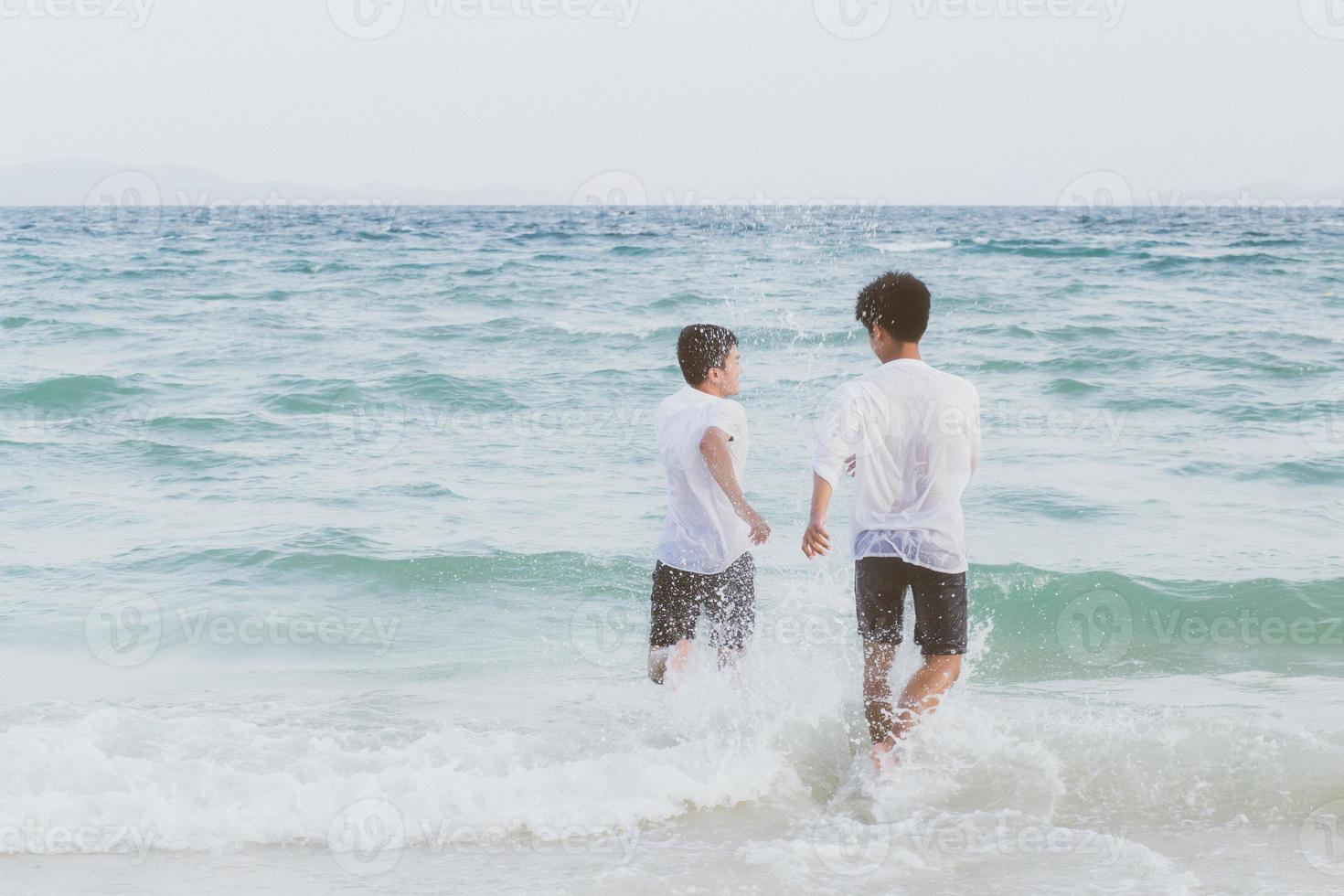 homosexuella porträtt ungt asiatiskt par springer med glada tillsammans på stranden på sommaren, asien gay turism för fritid och koppla av med lycka i semestern till sjöss, hbt juridiskt koncept. foto