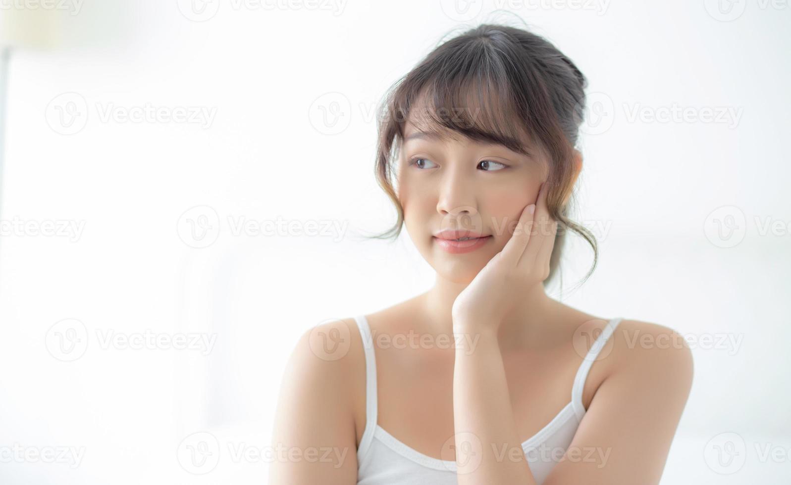 porträtt av vacker ung asiatisk kvinna leende medan vaknar frisk och välbefinnande med soluppgången på morgonen i sovrummet, asien flicka hudvård med glad med fräsch, livsstil och slappna av koncept. foto