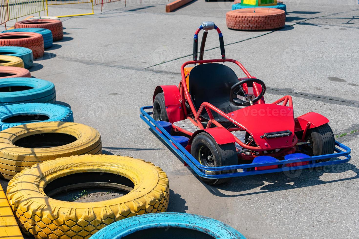 utomhus karting och en röd elektrisk sportbil på en racerbana utrustad med skyddande trottoarkanter gjorda av gamla däck foto