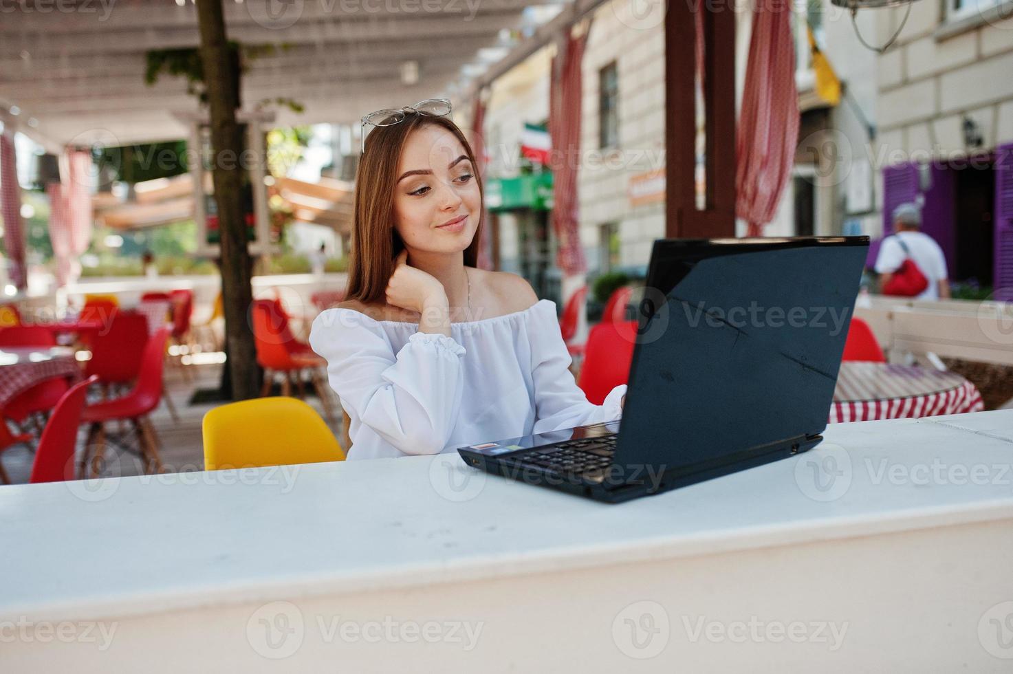 porträtt av en stark oberoende framgångsrik affärskvinna som bär smarta vardagskläder och glasögon som arbetar på en bärbar dator på ett kafé. foto