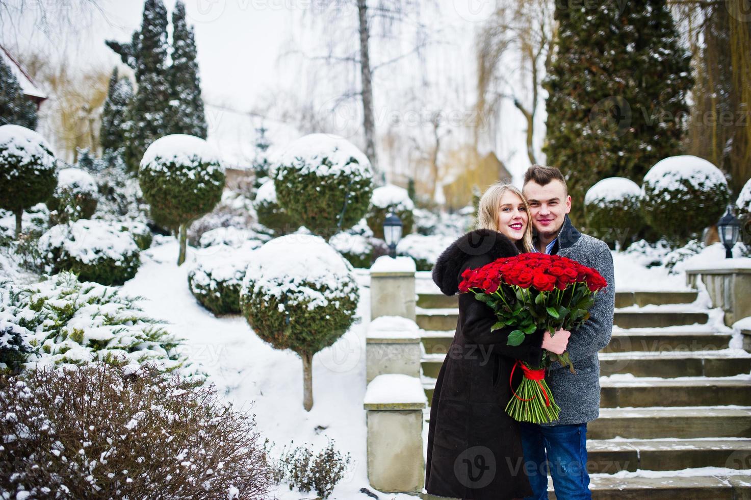 älskande par i kärlek på vinterdagen med stor bukett av 101 rosor. foto