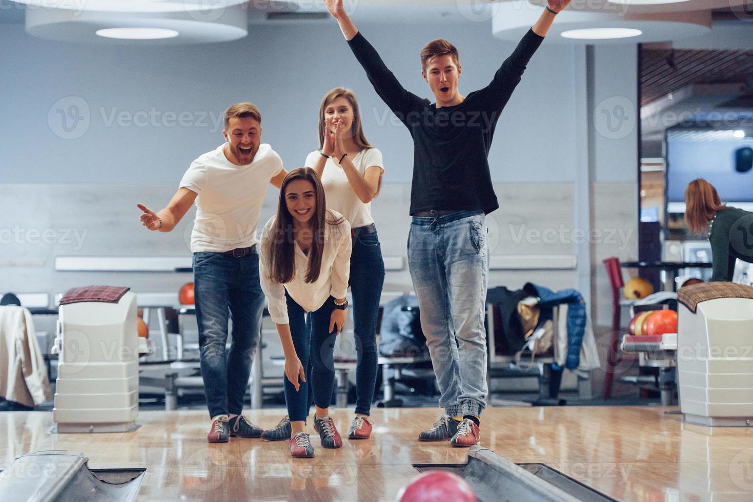 du kan göra strejken. unga glada vänner har kul i bowlingklubben på sina helger foto