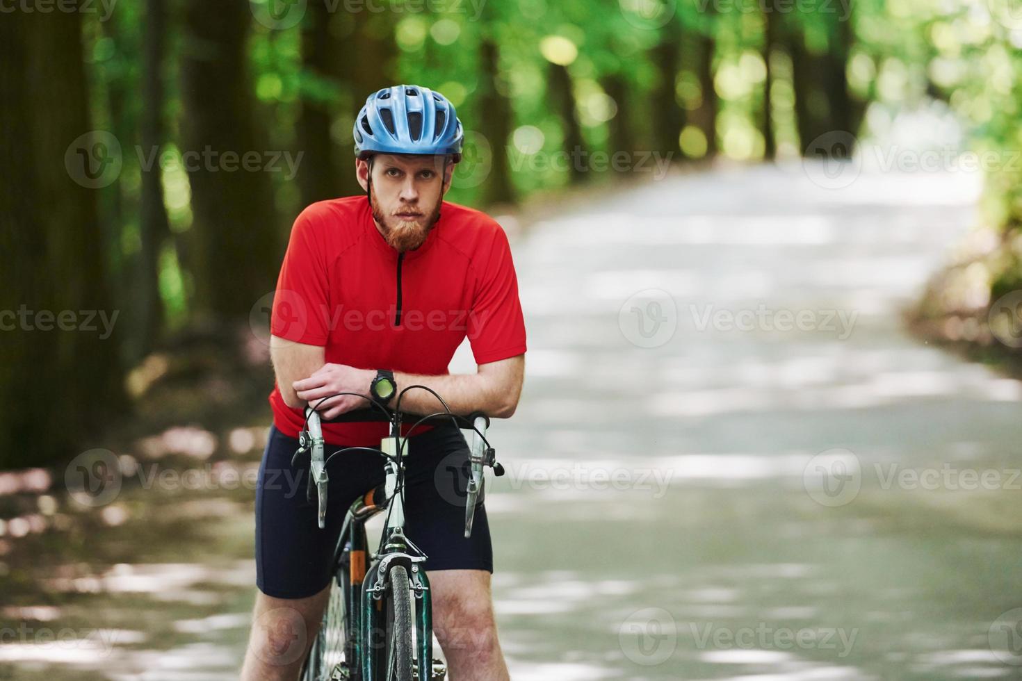 tar en rast. cyklist på en cykel är på asfaltvägen i skogen på en solig dag foto