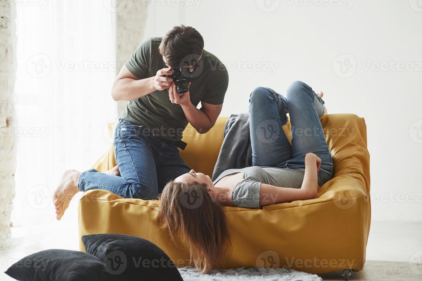 fortsätt se ut så. fotograf tar en bild av ung flicka som ligger på den vita soffan foto